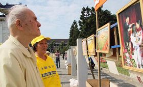 排字的四周同时展出“大法弟子证实法摄影作品展”，市民认真地观看作品集，及听取法轮功学员的解说