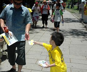 七月十八日屏东学员在鹅銮鼻讲真相，图为小弟子分送真相材料给行人