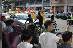 法轮功学员的游行沿路吸引了许多民众驻足观赏。