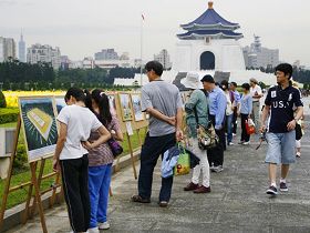 许多路过的游客，围观在法轮功的真相图片展前