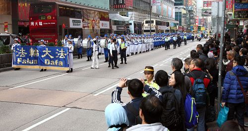 法轮功阵容庞大整齐的游行队伍吸引中西游客及港民驻足观看，纷纷举起相机、手机拍照。