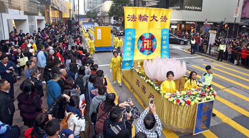 法轮功阵容庞大整齐的游行队伍吸引中西游客及港民驻足观看，纷纷举起相机、手机拍照。