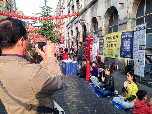 图10：一位中年华人男士认真摄下法轮功学员的炼功场面和真相横幅。