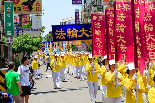 庆祝活动学员们精神抖擞举着旗帜和横幅，上面写着：“庆祝世界法轮大法日”、“法轮大法好”、“真、善、忍”等与民众分享修炼的喜悦。