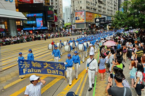 “图2：天国乐团引领法轮功学员队伍，游行从港岛区英皇道、轩尼诗道，途经闹市铜锣湾、湾仔、中环，最终到西环中联办，历时三个多小时，沿途吸引港民及中西旅客观看。"