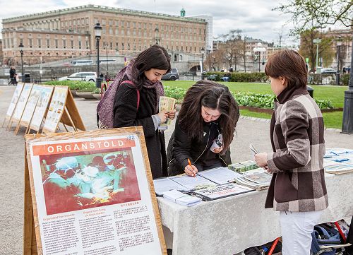 了解真相后的人们在反活摘器官的签名册上签名，支持法轮功学员反迫害。