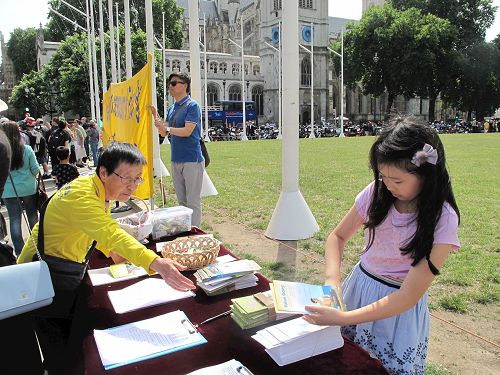 '图4：二零一七年七月十八日，小法童（右一）和爸爸一起参加在英国议会大厦前参加法轮功学员讲真相反迫害活动'