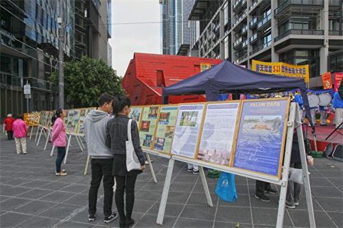 '图4：墨尔本法轮功学员在市中心亚拉河畔的女王桥广场（Queensbridge Square）庆祝“世界法轮大法日”。路人驻足阅读展板。'