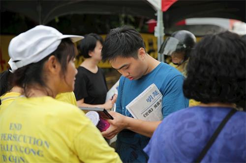 '图12：刚来台湾工作两个月的越南翻译工作者武先生（中），拿到台南的炼功点资讯很感动。'