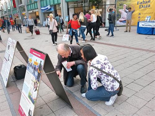 '图5：两位路人蹲下阅读真相展板。'