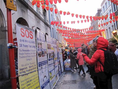 '图10：二零一九年二月十日晚，一对来自立陶宛（Lithuania）的母女在伦敦唐人街认真了解法轮功真相'