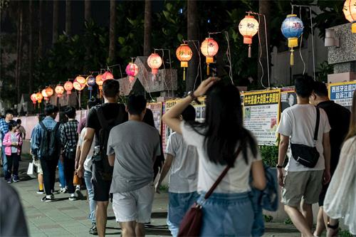 '图3：庆祝和迎接“世界法轮大法日”的到来，五月十一日华灯初上，法轮功学员们在瑞丰夜市张灯结彩，摆好真相长城，让路过民众了解真相。'