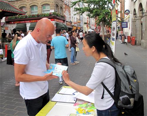 图7：二零一九年六月一日，斯图尔德（Steward）在伦敦唐人街听法轮功学员温迪讲真相后签名反迫害